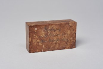 Briefbeschwerer aus einer Mauerstütze. Inschrift „Erinnerung an die Stütze des alten Burgtheaters“