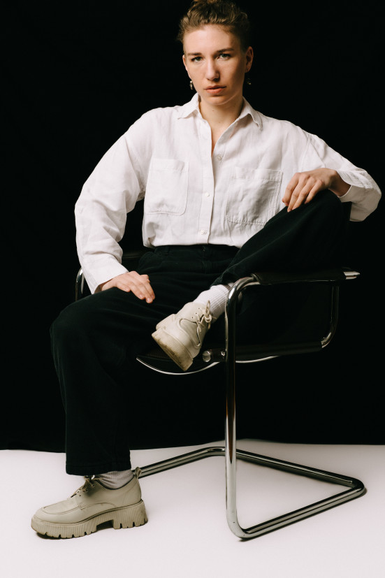 Foto der Bühnenbildnerin Mirjam Stängl sitzend auf einem Stuhl in farbe