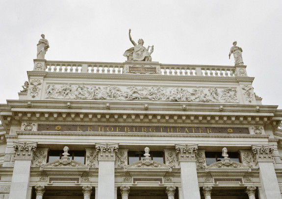 Über dem Eingangsportal steht mit goldenen Buchstaben "K & K Hofburgtheater"