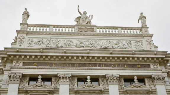 Über dem Eingangsportal steht mit goldenen Buchstaben "K & K Hofburgtheater"